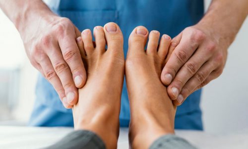 front view of male osteopathic therapist checking female patient s toes 1